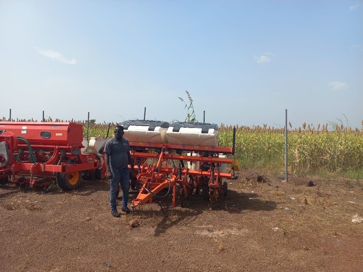 Planting equipment staged beside a ripening sorghum field